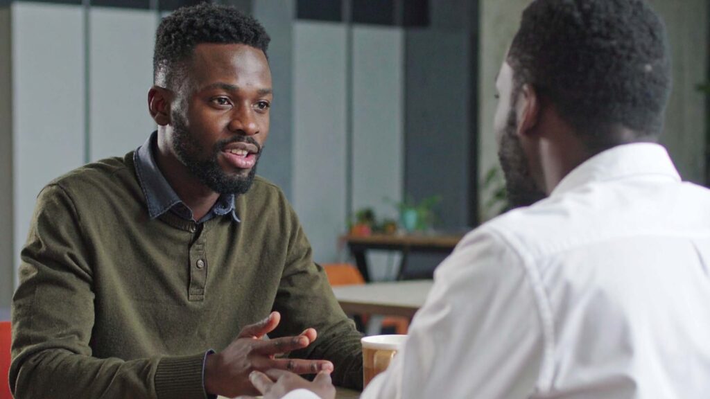 Two African-American brothers talking at the table.