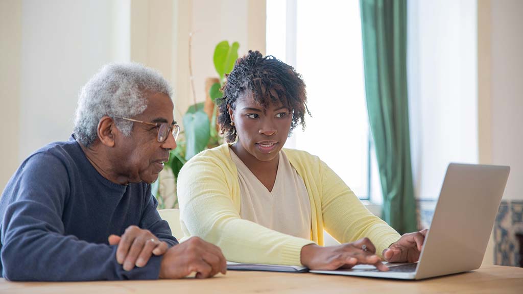 African-American woman and her elderly dad looking at the computer